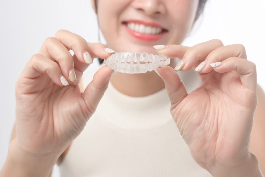 Person holding clear Invisalign aligners.