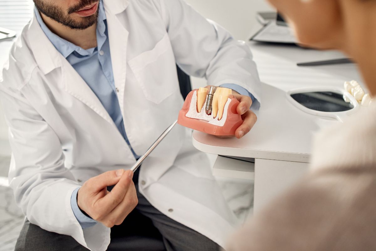 Dentist showing dental implant model to a dental patient during consultation.