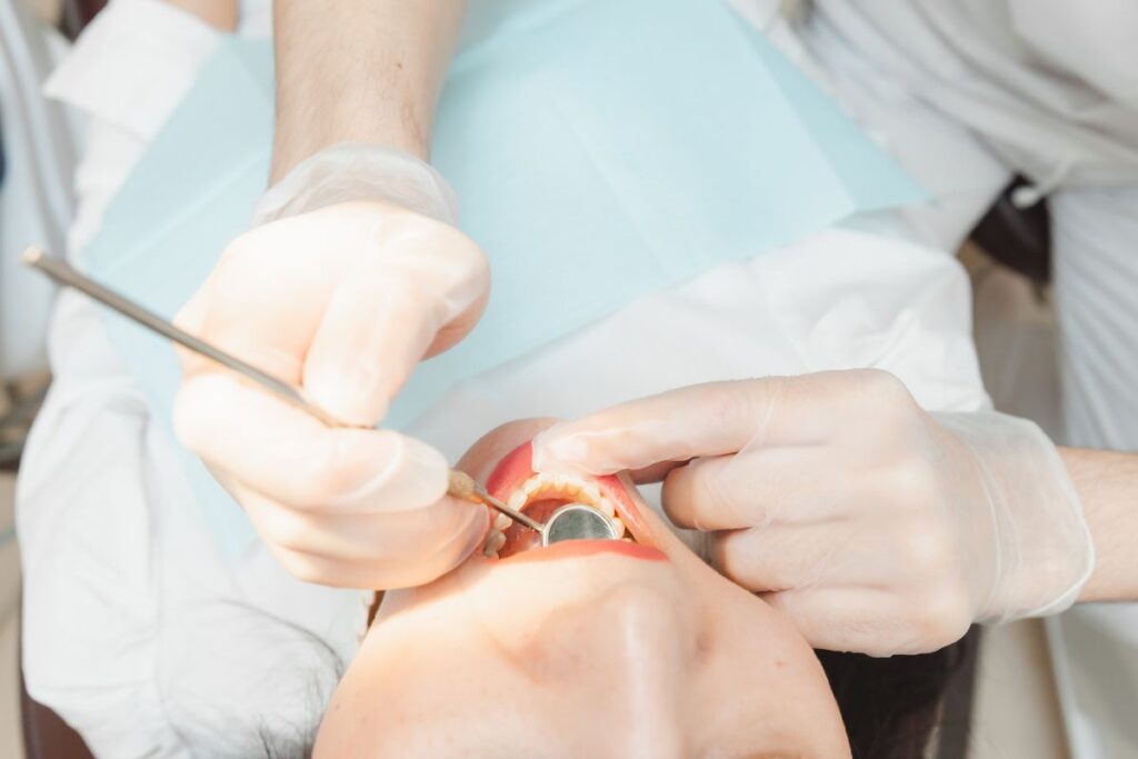 Dentist examining infected tooth with a tool.