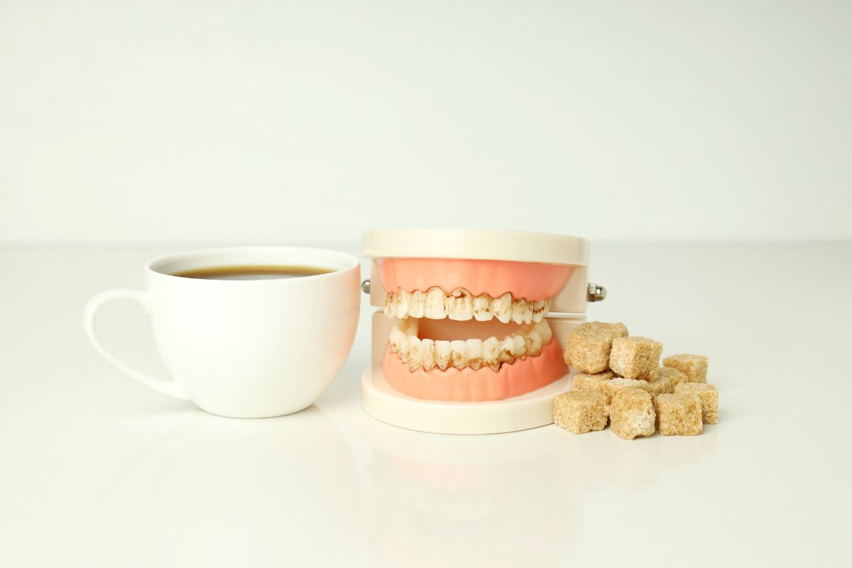 Dental model with sugar cubes and coffee cup, illustrating common myths and realities about sugar’s impact on teeth and oral health.