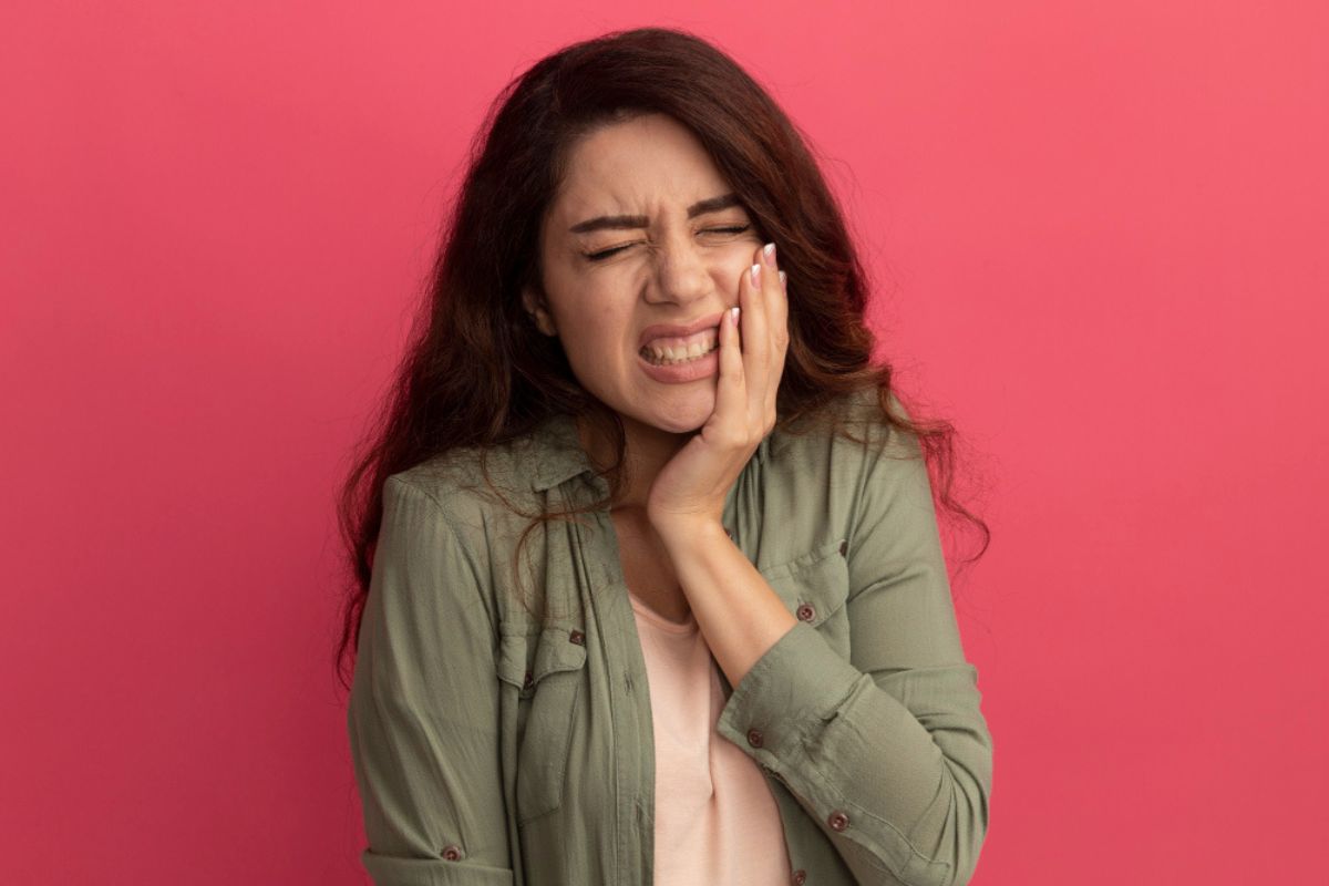 Woman holding jaw in severe tooth pain, indicating urgent dental issue requiring immediate care.