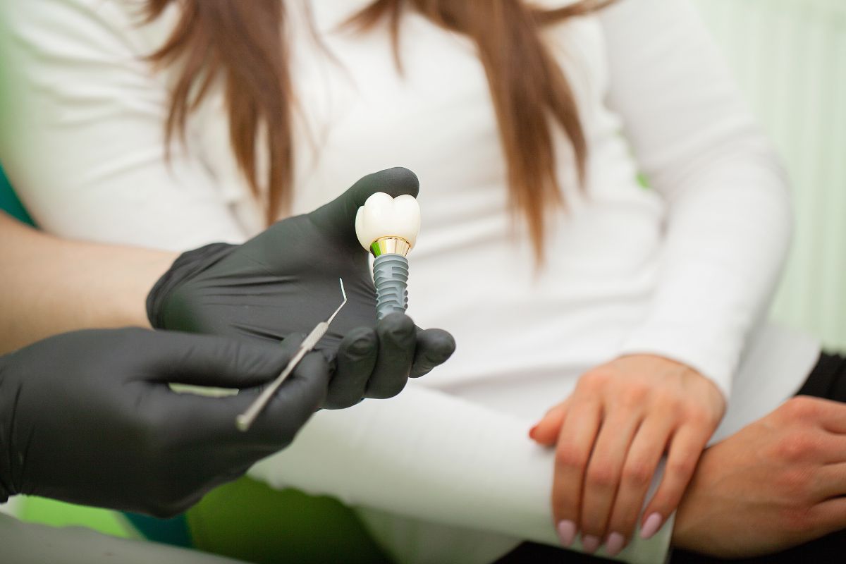 Dentist explaining a dental implant before implant surgery consultation.